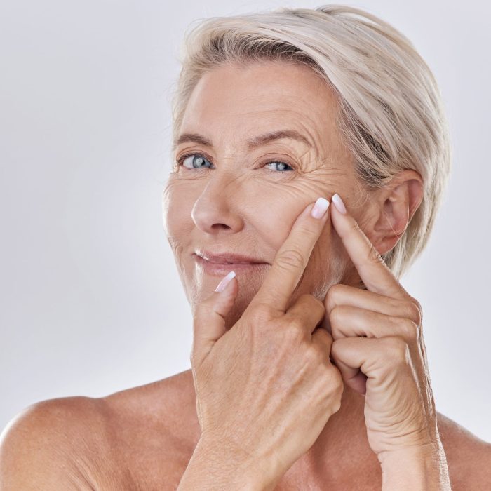 Acne or pimple popping female or woman after night face skincare beauty treatment for healthy and clear skin copy space. Portrait of happy senior woman use cosmetics with hands to target wrinkles.